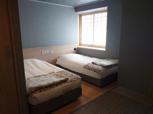a small bedroom with two beds and a window at Hotel Isago Kobe in Kobe
