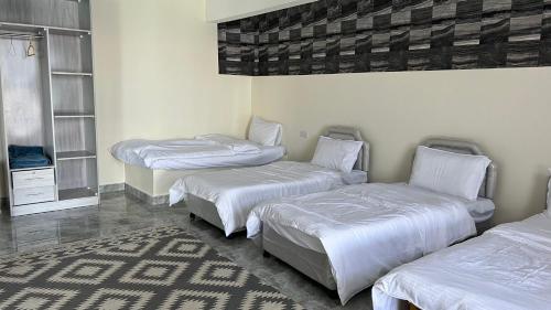 a room with three beds with white sheets and a rug at Wadi Shab Beach Villa in Sur