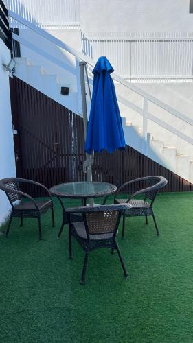 a table with a blue umbrella and three chairs at Wadi Shab Beach Villa in Sur