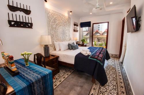 ein Hotelzimmer mit einem Bett und einem Tisch in der Unterkunft Khmer Surin Boutique Guesthouse in Phnom Penh