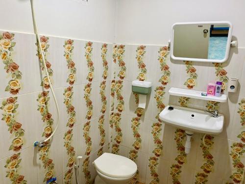 ein Badezimmer mit einem WC, einem Waschbecken und einem Spiegel in der Unterkunft TR Bungalow in Ban Tha Rua