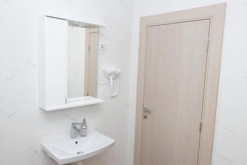 a white bathroom with a sink and a mirror at Millennium Apartment in Bačka Palanka