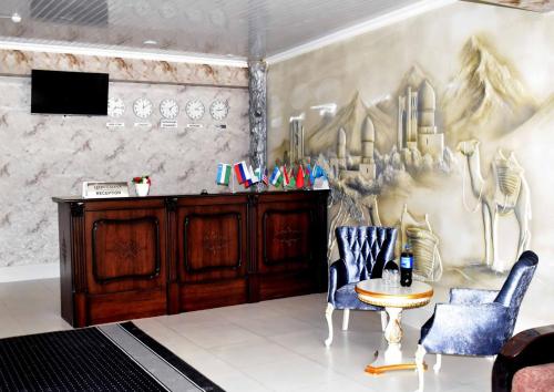サマルカンドにあるOsiyo Hotelの椅子2脚とテーブル1台が備わる壁の客室です。