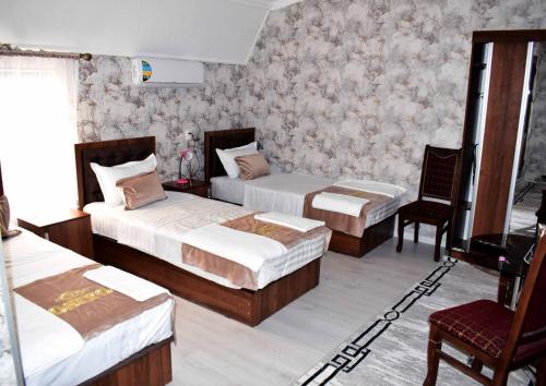 a hotel room with two beds and a chair at Osiyo Hotel in Samarkand