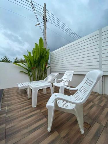 three white chairs and a table on a deck at Pool Villa Sattahip White House in Sattahip