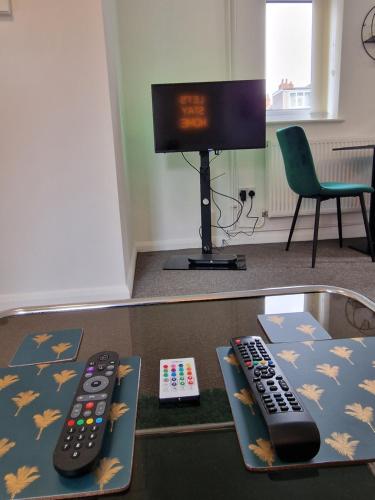 two remote controls sitting on a table with a tv at 1 Bed @ Factory Quater - Chard St in Nottingham