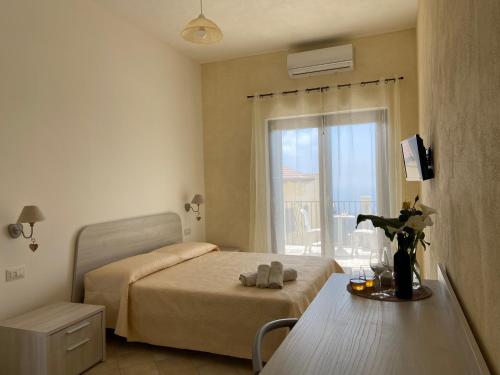 Schlafzimmer mit einem Bett, einem Tisch und einem Fenster in der Unterkunft Tenuta Vallina - Golfo di Policastro in Tortorella