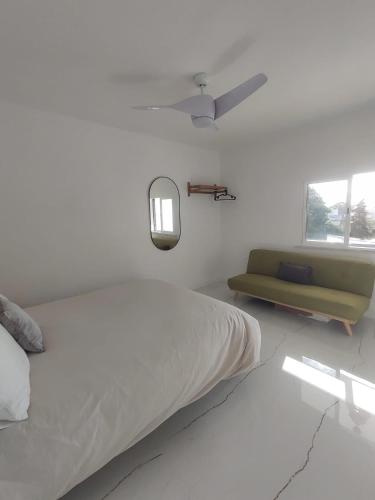 a white bedroom with a bed and a green couch at Casa da paz #2 in Vila Nova de Milfontes
