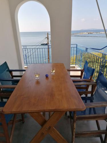 a wooden table with two wine glasses on a balcony at Villa Evmenia Panoramic sea view & Sea front apartments in Skopelos Town