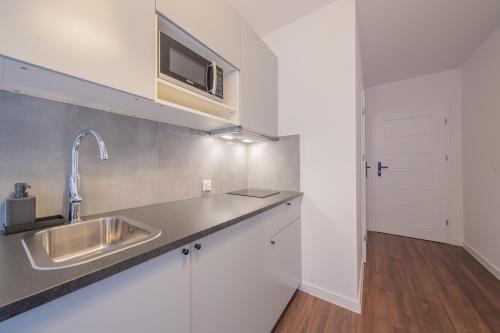 eine Küche mit Spüle und Mikrowelle in der Unterkunft TinyRooms in Kattowitz