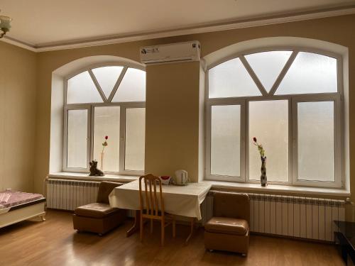 a dining room with two windows and a table and chairs at Beaming_House in Sheki