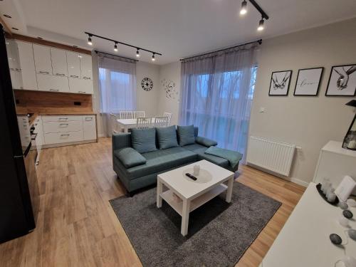 ein Wohnzimmer mit einem blauen Sofa und einem Tisch in der Unterkunft Apartament na Letniej in Kłodzko