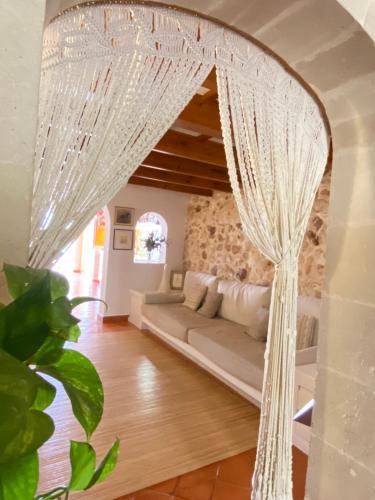 uma sala de estar com um sofá branco e cortinas em Santa Rosalia em Ciutadella