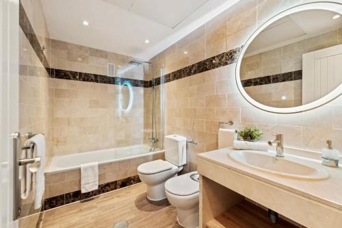 een badkamer met een wastafel, een toilet en een spiegel bij Royal Marbella Resort Pool Golf Beach & Bars in Estepona