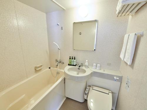 a bathroom with a sink and a toilet and a tub at Hotel Courtland in Nagano