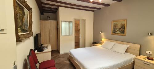 um quarto com uma cama branca e uma cadeira vermelha em Alliance Hotel Ieper Centrum em Ypres