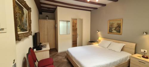 a bedroom with a white bed and a red chair at Alliance Hotel Ieper Centrum in Ieper