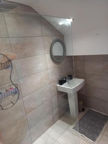 een badkamer met een douche, een wastafel en een spiegel bij Flat 4, 43 Part Street in Southport