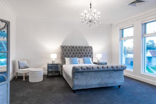 a bedroom with a bed and a chair and a chandelier at Swainson on Fawnbrake in Henley Beach South
