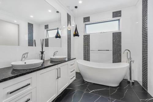 a white bathroom with two sinks and a tub at Swainson on Fawnbrake in Henley Beach South