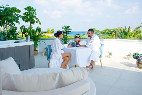 a man and a woman sitting at a table on a patio at At Herbal Boutique Hotel & Spa in Protaras
