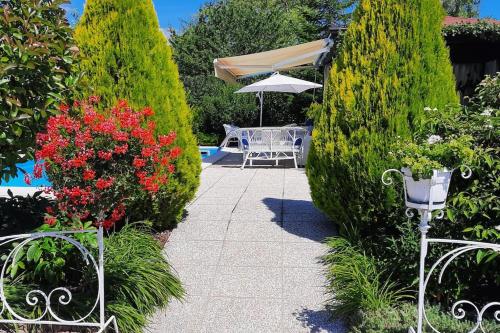 a garden with a table and an umbrella and some bushes at Villa Lara in Marsaglia