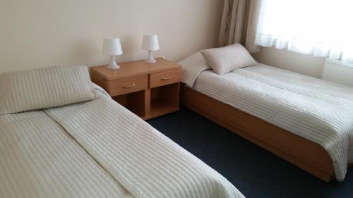 two beds in a room with two lamps on night stands at Hotel Dom Polonii in Ostróda