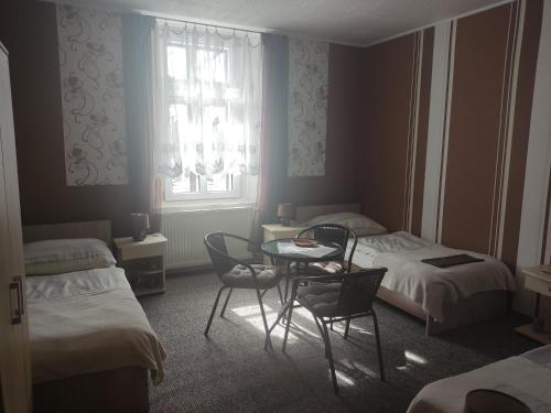 a room with two beds and a table and chairs at Penzion U Soudu in Hora Svatého Šebestiána