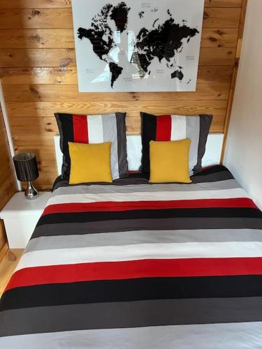 a bedroom with a large bed with yellow and red pillows at Chalet 2 personnes avec jacuzzi privatif et piscine saisonnière partagée in Corcieux