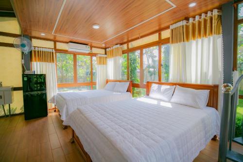 two beds in a room with windows at HomesStay Lê Thạnh in Ho Tram