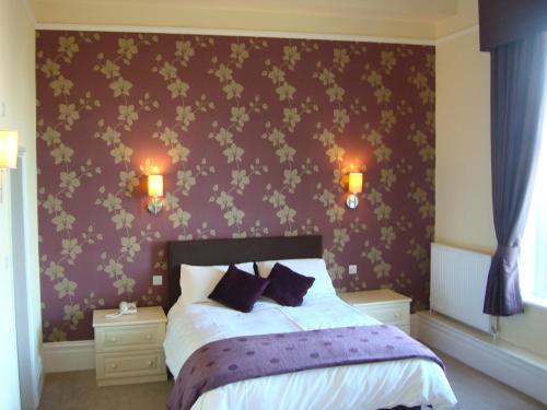 a bedroom with a bed with a purple wall at The North Euston Hotel in Fleetwood