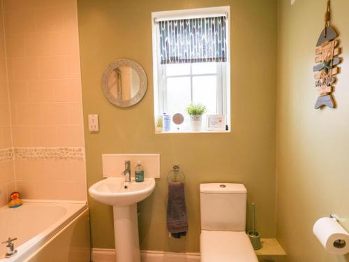 ReightonにあるSandcastle Cottageのバスルーム(洗面台、トイレ付)、窓が備わります。