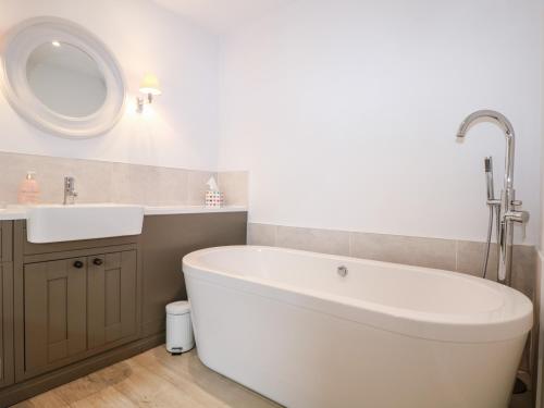baño con bañera blanca grande y lavamanos en Fox's Den en Fareham