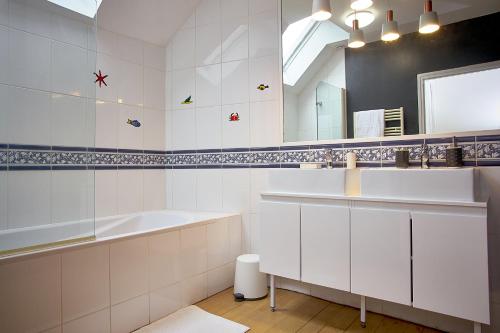 a white bathroom with a sink and a mirror at Gîte l'écurie in Larçay