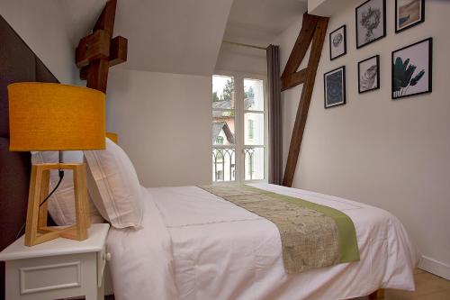a bedroom with a bed with a lamp and a window at Gîte l'écurie in Larçay