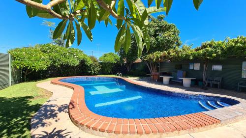 a swimming pool with a brick pathway around it at Travelway Motel in Port Pirie