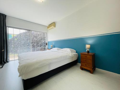 - une chambre avec un grand lit et un mur bleu dans l'établissement REA Lodge, à Punaauia