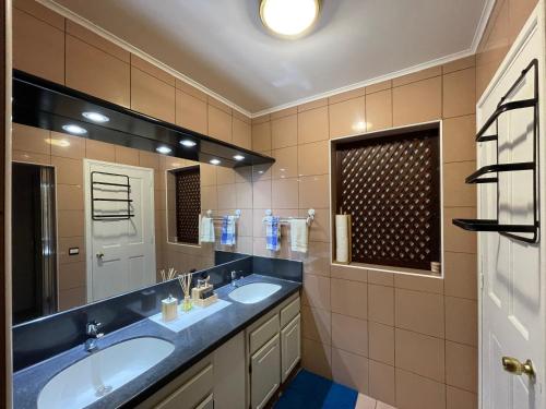 La salle de bains est pourvue de 2 lavabos et d'un grand miroir. dans l'établissement REA Lodge, à Punaauia