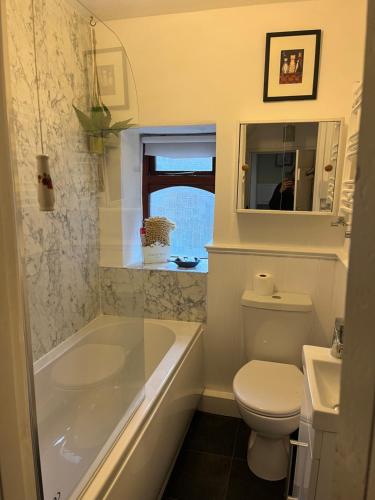 a bathroom with a tub and a toilet and a sink at Wicket Green Cottage in Hayfield