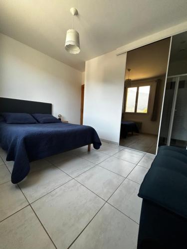 een slaapkamer met een blauw bed en een spiegel bij Gîte San Jordi in Duilhac
