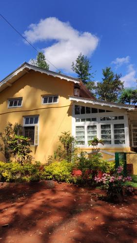 a yellow house with flowers in front of it at Citadel Resort in Panchgani