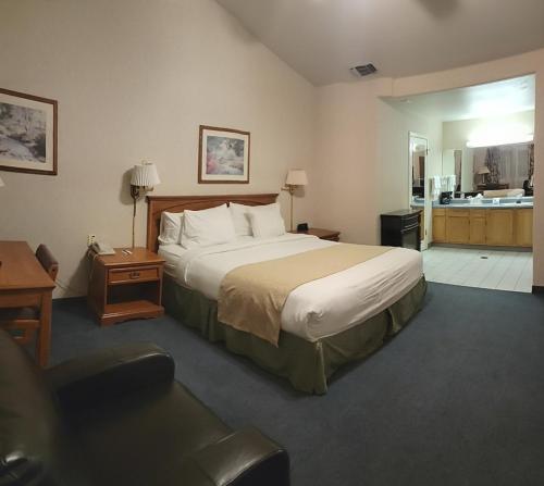 a hotel room with a large bed and a kitchen at Garden Inn and Suites Fresno in Fresno
