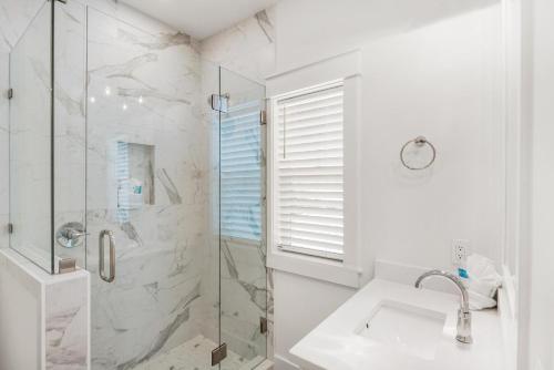 a white bathroom with a shower and a sink at The Eagles Nest in Rosemary Beach