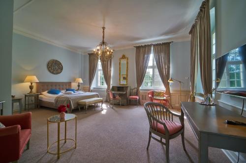 イェレニャ・グラにあるPałac Łomnica - Karkonosze / Riesengebirgeのベッド、テーブル、椅子が備わるホテルルームです。