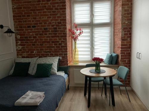 - une chambre avec un lit, une table et un mur en briques dans l'établissement przytulnie w Łodzi, à Łódź