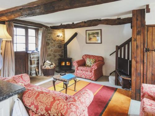 a living room with a red couch and a tv at The Cottage in Moretonhampstead