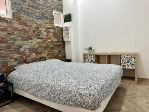 - une chambre avec un lit et un mur en briques dans l'établissement l'Annexe, à Rhinau