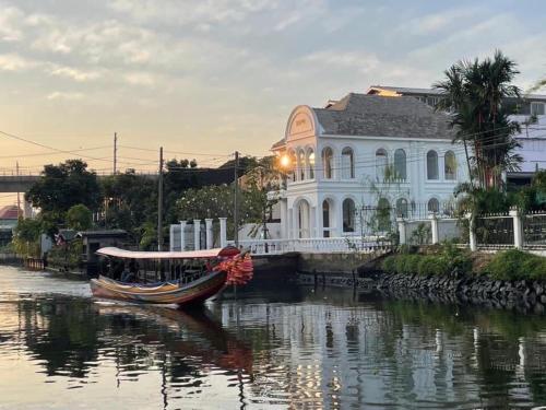 a boat in the water in front of a building at Arpo Pool Villa Riverside Bangkok in Bangkok