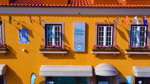 a yellow building with windows and flags on it at Sea Garden, Residência in Peniche