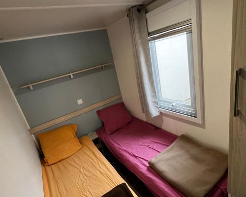 Cette petite chambre comprend 2 lits et une fenêtre. dans l'établissement Mobil homme proche de la mer, au Grau-du-Roi